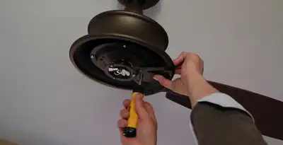 Electrician installing ceiling fan mounting bracket and fixture in Waltham, MA