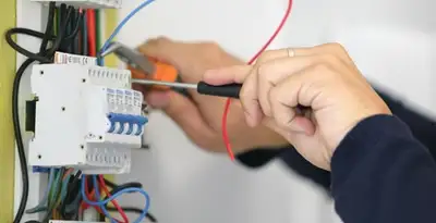 Electrician installing and adjusting circuit breakers in an electrical panel in Waltham, MA