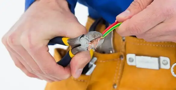 licensed electrician securing electrical wiring with professional tools during service work in Waltham, MA