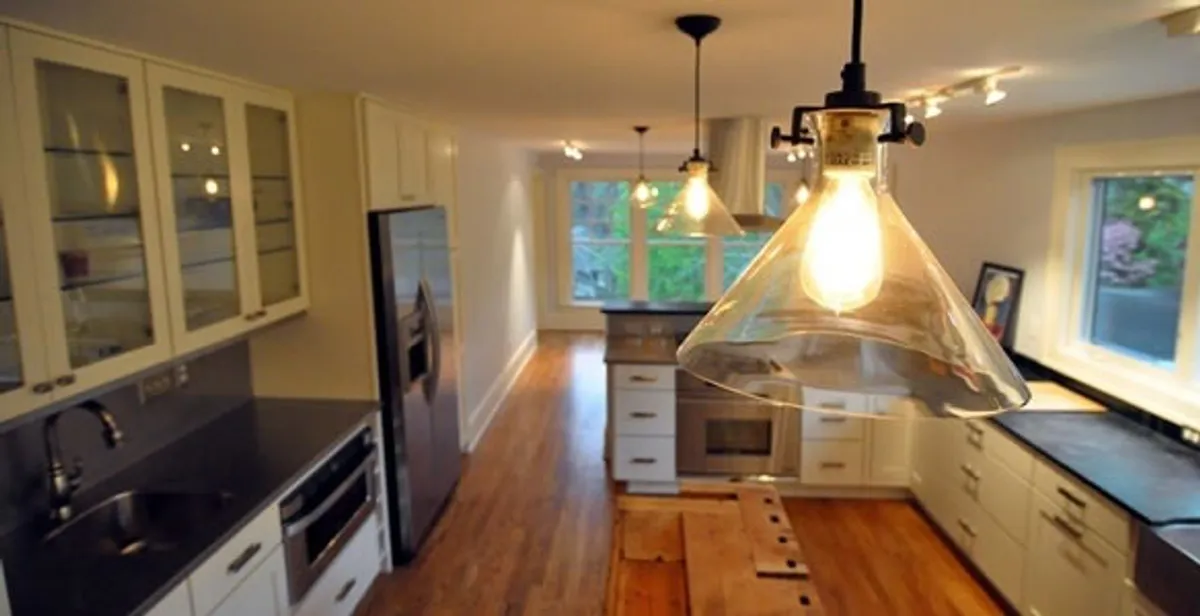 Residential electrician installing modern indoor light fixture in a home in Waltham, MA