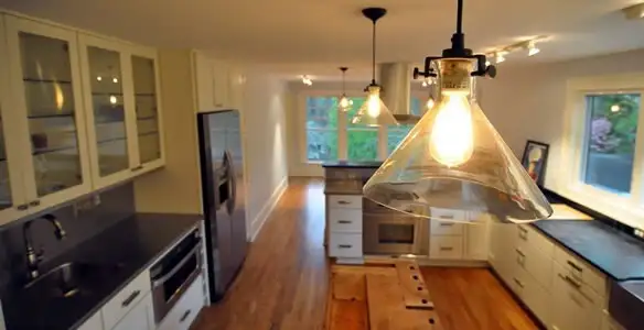 Residential electrician installing modern indoor light fixture in a home in Waltham, MA