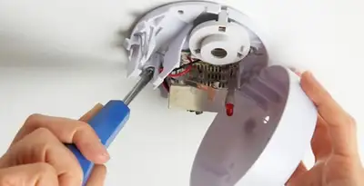Certified technician wiring smoke detector during installation in Waltham, MA